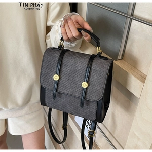 Détail du rabat en sergé gris et des lanières en cuir noir avec boucles dorées sur le sac à dos