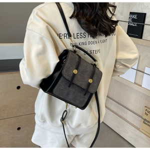 Détail d'un mini sac à dos en cuir noir avec rabat texturé gris et boucles dorées