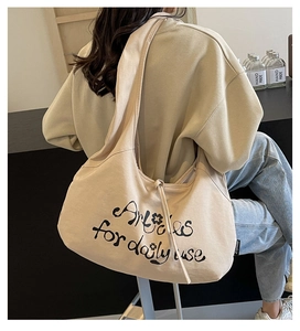 Close-up of beige canvas hobo bag with black letter print and soft fabric texture