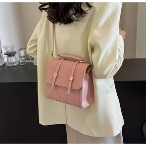 Vue latérale d'un sac bandoulière matelassé rose avec fermoirs dorés et blazer ivoire