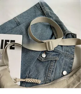 Detailed shot of beige nylon crossbody bag featuring adjustable wide shoulder strap and zipper