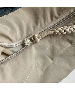 Macro shot of smooth metal zipper head and woven drawstring detail on a nylon bag