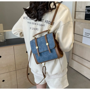 Détail du sac bandoulière en denim bleu avec bordure en cuir marron et boutons dorés rétro