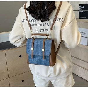 Détail du mini sac à dos en denim bleu avec lanières en cuir marron et rivets dorés