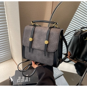 Détail montrant la texture du tissu sergé gris et la bride en cuir noir avec boucle dorée