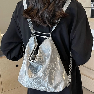 Silver metallic backpack with glossy wrinkled texture and chain strap worn by a model
