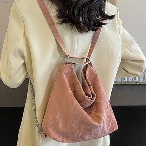 Pink pleated tote bag with chain strap shown as a stylish backpack on a model