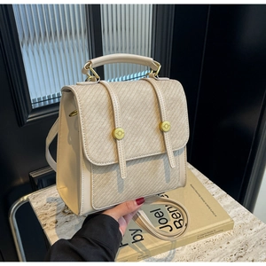 Détail d'un sac à dos blanc crème minimaliste avec texture toile et boucle en métal doré