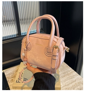Détail du sac à main rose avec pendentif en perles et bandoulière réglable