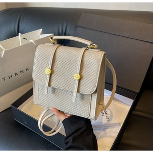 Détail du sac à dos crème avec gaufrage diagonal, ferrures dorées et sangles en cuir