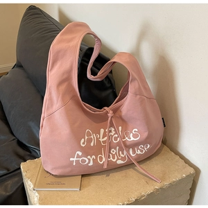 Detail of pink canvas dumpling bag with Articles for daily use print on stone stand