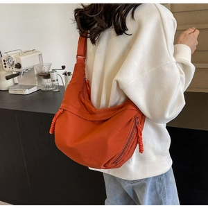Close-up of bright orange nylon crescent bag with textured woven rope zipper pullers