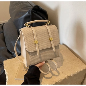Détail du sac à dos beige avec texture à vagues diagonales et boucles dorées