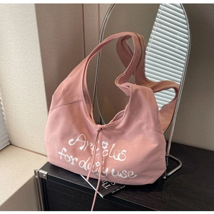 Pink canvas hobo bag detail with white slogan print and drawstring ribbon accents