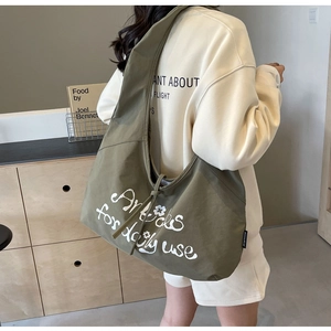 Detail view of large olive green canvas dumpling bag with white typography and floral print