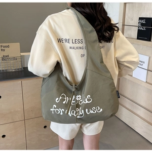 Detail of olive green canvas tote bag with white lettering and drawstring texture