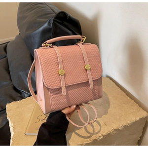 Mini sac à dos rose matelassé avec détails dorés et poignée sur un socle en pierre