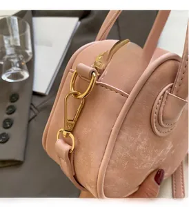 Détails de la fermeture éclair dorée et de la texture en cuir mat du sac Boston rose