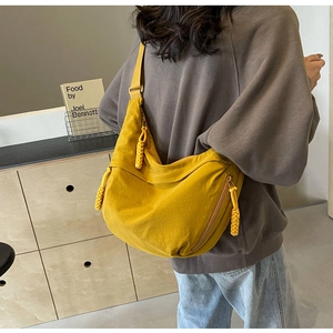 Detail of yellow nylon crescent bag featuring zip pockets and woven zipper pullers