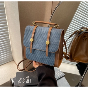 Vue détaillée du sac à dos en jean bleu vintage avec finitions en cuir marron
