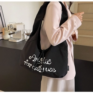 Close-up of black canvas tote bag featuring white script lettering for daily use
