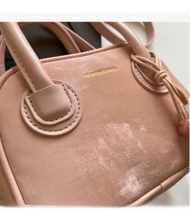 Détail du sac à main en cuir rose pêche montrant le logo doré et les finitions