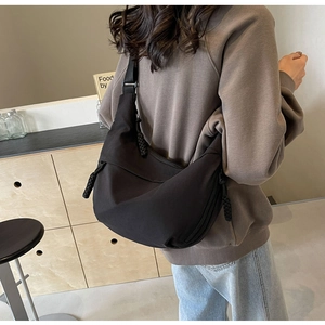 Detailed back view of black nylon crescent bag showing capacity and woven zipper pull