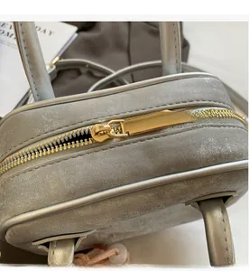 Détail d'une fermeture éclair en métal doré lisse sur un sac à main gris texturé