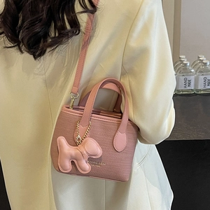 Borsa a secchiello rosa intrecciata con ciondolo a cane e catena d'oro indossata