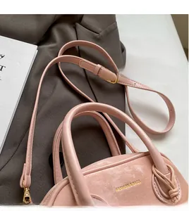 Vue détaillée du sac à main rose avec lettrage doré posé sur un blazer gris chic
