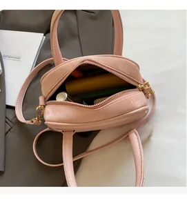 Vue de dessus d'un petit sac bandoulière rose pâle montrant l'espace intérieur