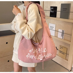 Pink canvas hobo shoulder bag with daily use text shown in a cozy aesthetic setting