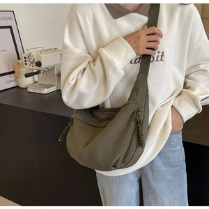 Detailed close-up of dark green nylon crescent bag with woven zipper pull and wide strap
