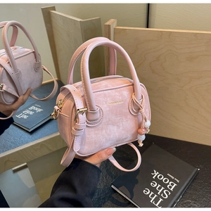Détail du sac à main Boston rose avec doubles poignées et breloque à pompon sur un miroir