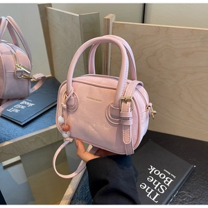 Détail du mini sac Boston rose clair avec logo mode et pompon décoratif en perles