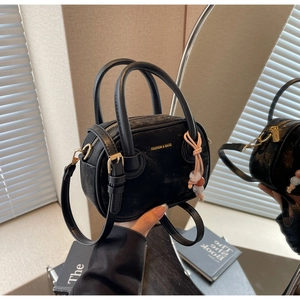 Détail du petit sac bandoulière noir avec finitions dorées et breloque en perles colorées