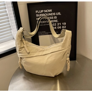 Detail of cream nylon crescent bag showing woven rope zipper and textured fabric