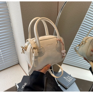 Détail du sac à bandoulière crème avec poignées rondes et breloque perlée à la mode