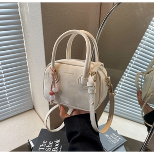 Détail du mini sac Boston crème avec marquage mode et breloque en perles roses