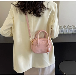 Mini sac Boston rose avec bandoulière et breloque perlée, porté par un mannequin