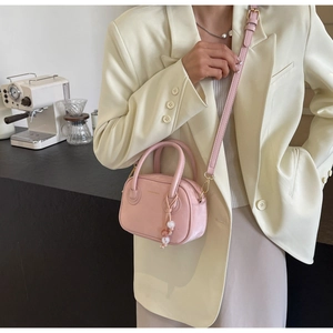 Gros plan du mini sac Boston rose avec breloque en perles et détail de bandoulière