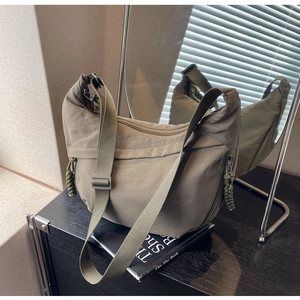 Detail view of military green nylon crescent bag with side pockets and zipper accents