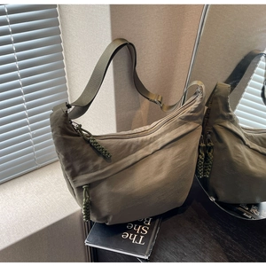Detail of dark green nylon hobo bag showing woven knot zipper and front pocket texture