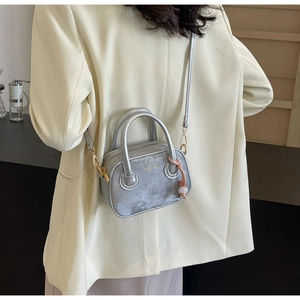 Détail du mini sac carré argenté avec deux poignées et pendentif en perles roses
