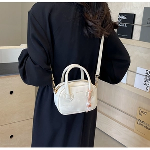 Sac bandoulière blanc minimaliste en cuir avec pendentif perlé en situation réelle