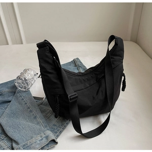 Detail of black nylon crescent hobo bag with adjustable wide strap and woven zipper pullers