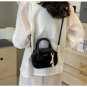 Détail du mini sac Boston noir avec lettrage doré et accessoire de charme en perles