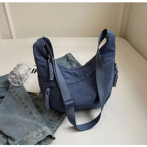 Detail of dark blue nylon crescent bag featuring a thick woven rope zipper puller