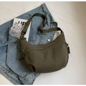 Detail of olive green nylon crescent bag with adjustable strap on blue denim jacket