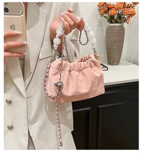Detail of pink pleated bucket bag with pearl bead handle and silver metal chain strap